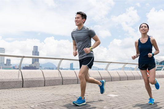 Two people jogging on a city promenade with skyscrapers in the background.