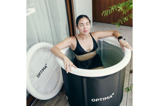 Woman sitting in an Optima cold plunge tub outdoors.